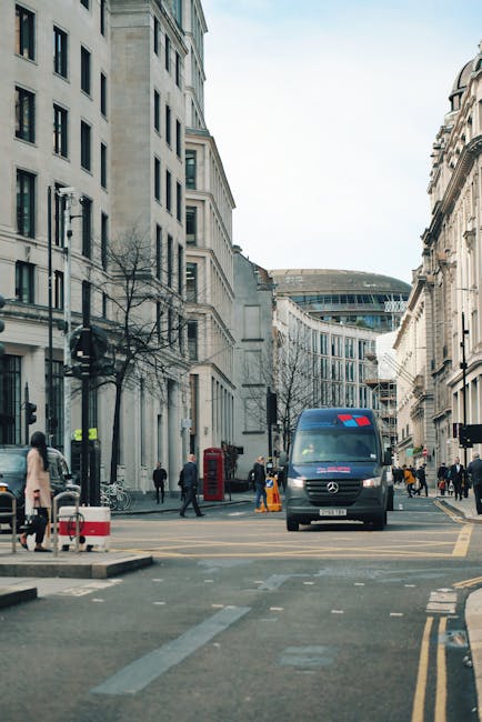 A street scene in Covent Garden, featuring a Mercedes-Benz van parked on the pavement near the entrance to a building with classical architecture. The van, used by Man With a Van Covent Garden for hom